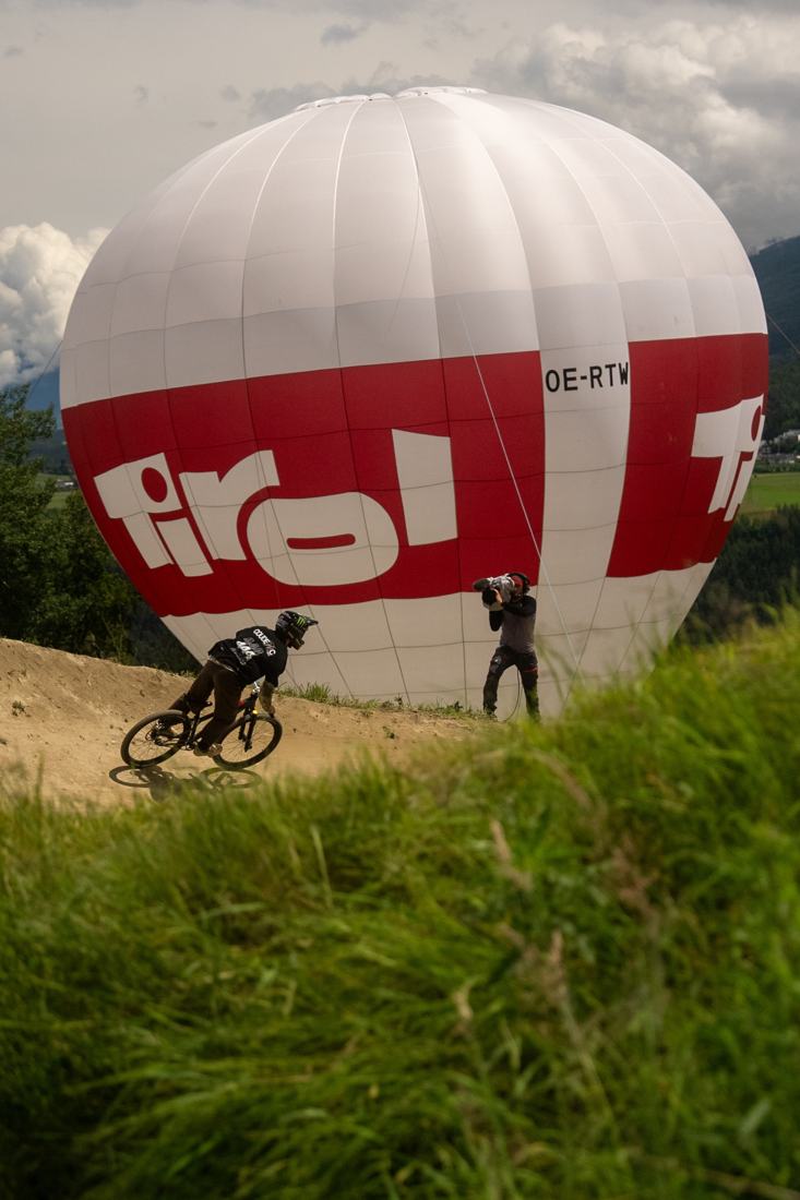 Mountain biker on a trail filmed in front of a Tirol hot-air balloon