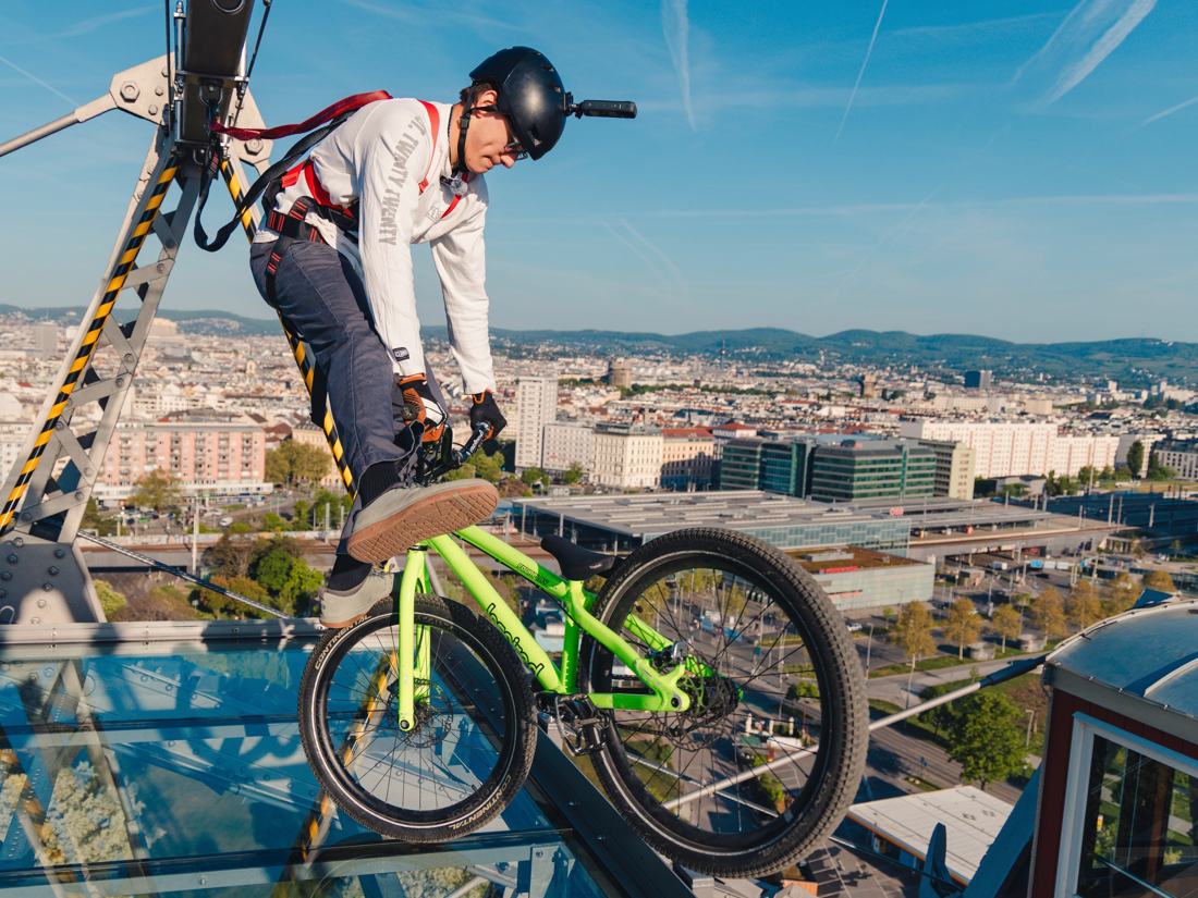Rider balancing a bike on top of the Vienna Riesenrad above the city